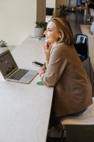 woman in brown coat using macbook air by Daria Pimkina courtesy of Unsplash.