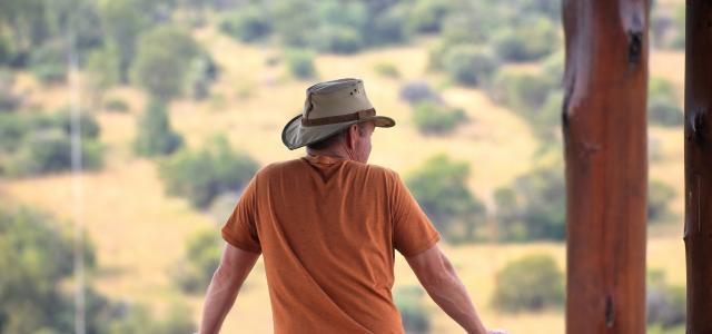 man in orange crew neck t-shirt and blue denim jeans sitting on brown wooden bench by Simon Hurry courtesy of Unsplash.